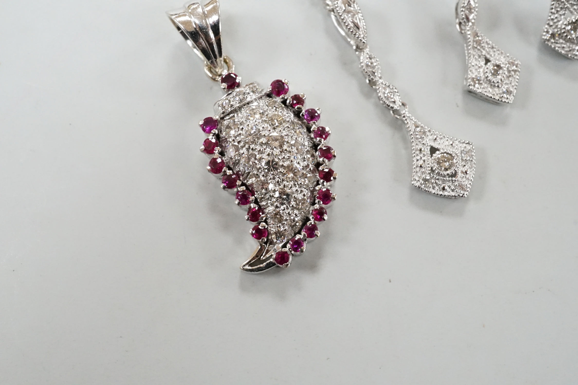 A modern white metal ruby and diamond cluster set drop pendant, modelled as a pear, overall 26mm, together with a modern 375 white metal pendant, 25mm, on a 9ct white gold chain and a pair of matching drop earrings, one